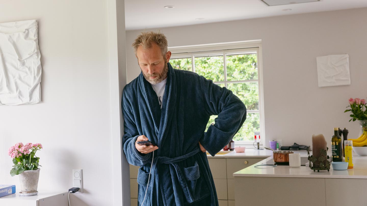 Mand i morgenkåbe tjekker sin mobiltelefon