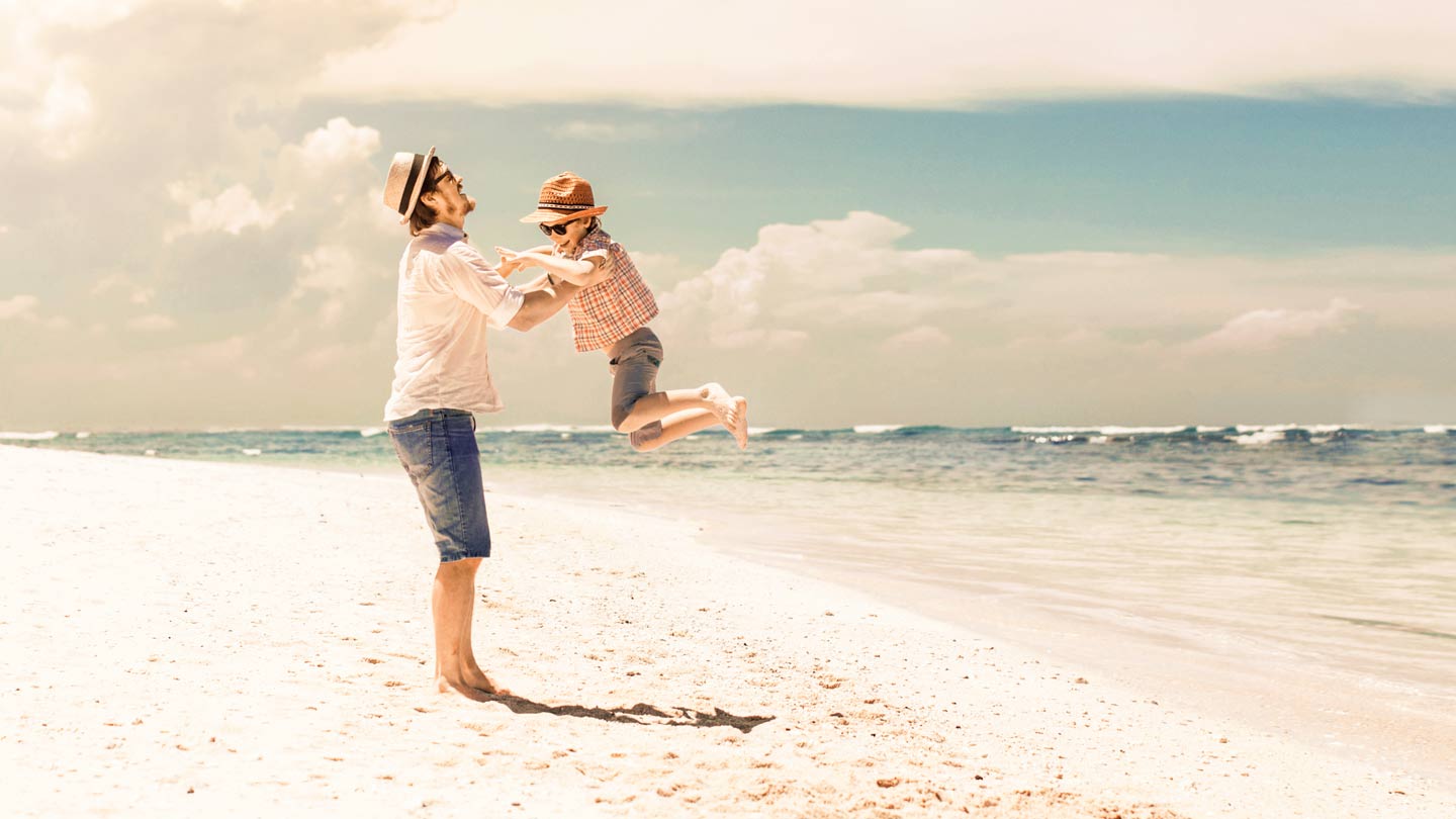 Far og barn leger på stranden