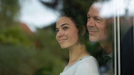 Mand og kvinde der holder om hinaden og ser ud ad vinduet