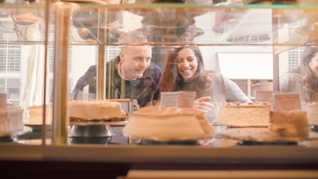 Couple looking at wedding cakes through window