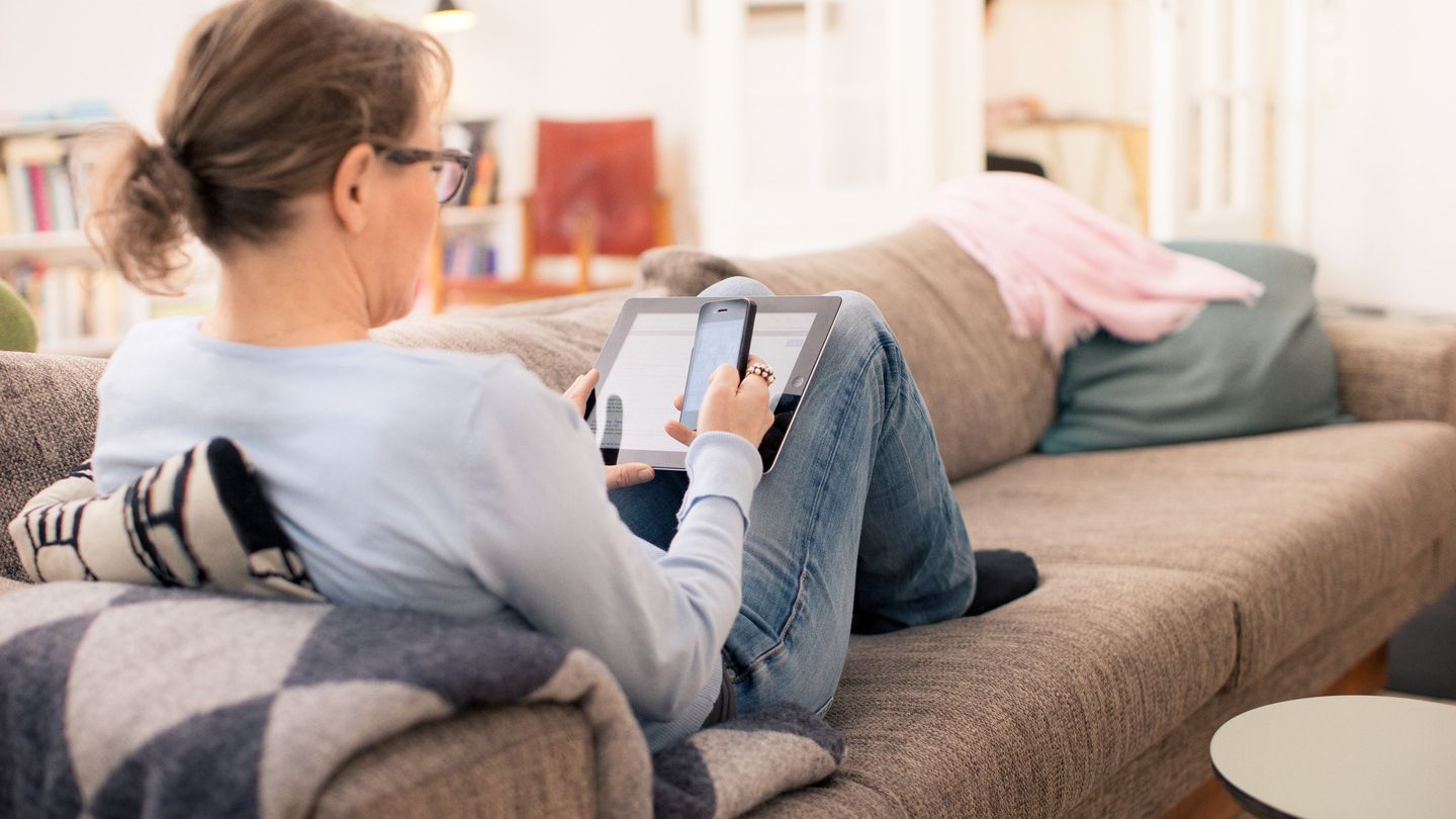 Kvinde der ligger i sofa med iPhone og iPad