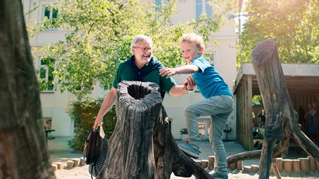 Bedstefar leger med barnebarn på legeplads.