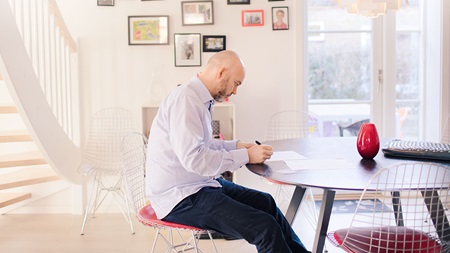 Man sitting at dinner table signing papers