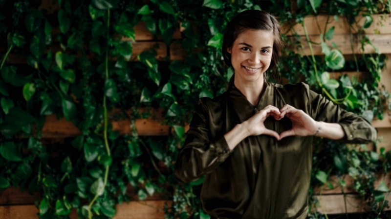Kvinde der står foran væg med grønne planter