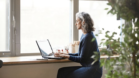 Woman is working on her laptop by the window