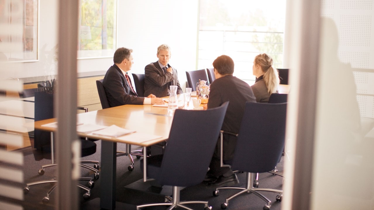 Fire mennesker der sidder i møde.