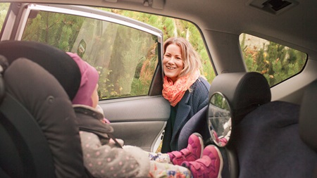 Mor smiler til lille datter i ny bil
