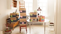 Marked moving boxes piled in the living room Flyttekasser stablet på bord og stole
