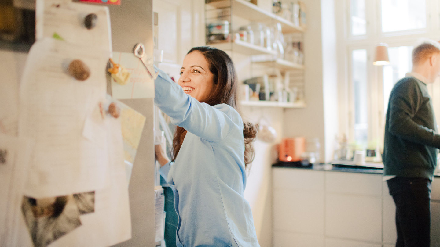Smilende kvinde står i køkken