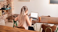 Kvinde sidder med computer ved spisebord