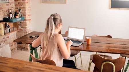 Kvinde sidder med computer ved spisebord
